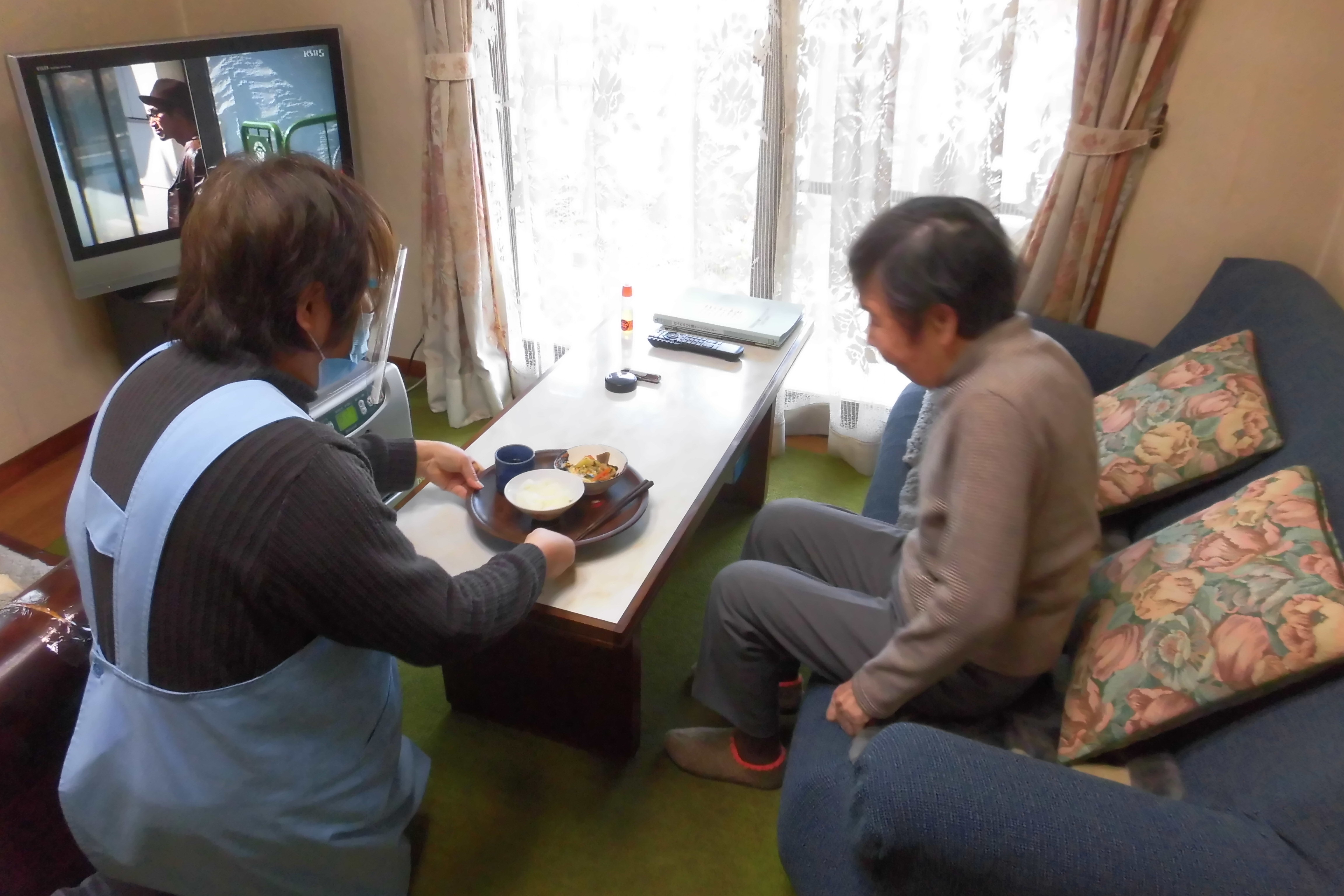 利用者さんの自宅で、利用者さんにヘルパーが食事を提供している写真