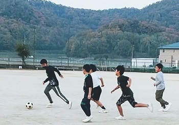 グラウンドでサッカーをする児童