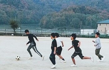 校庭でサッカーをする児童の写真